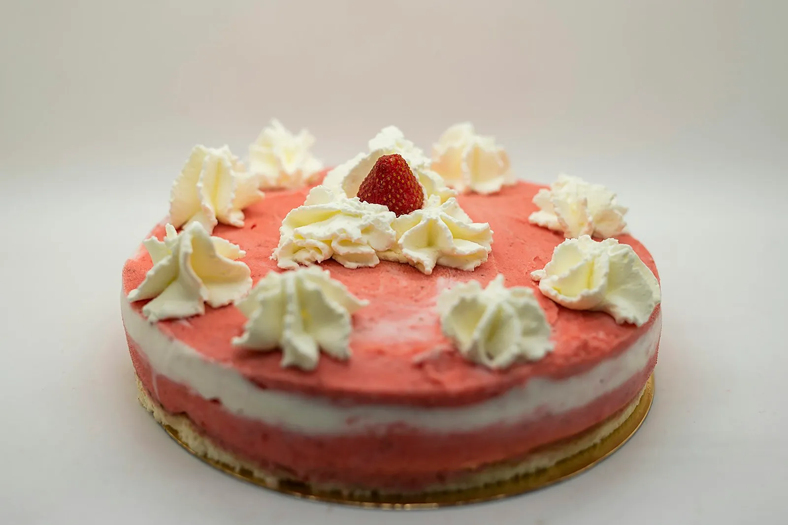 Erdbeer-Sahnetorte mit Sahnetupfen und einer Erdbeere