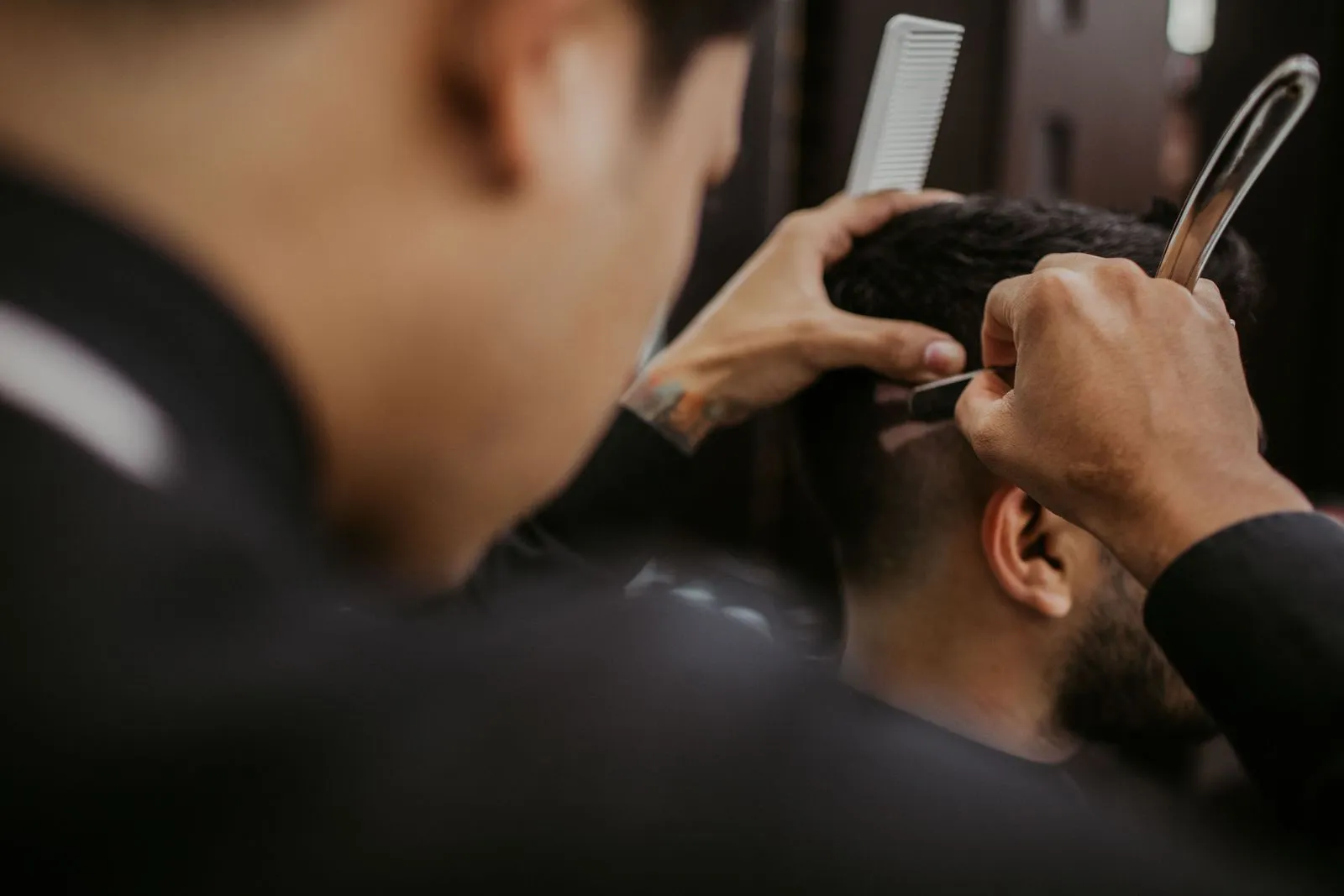 Barbier schneidet mit Schere und Kamm