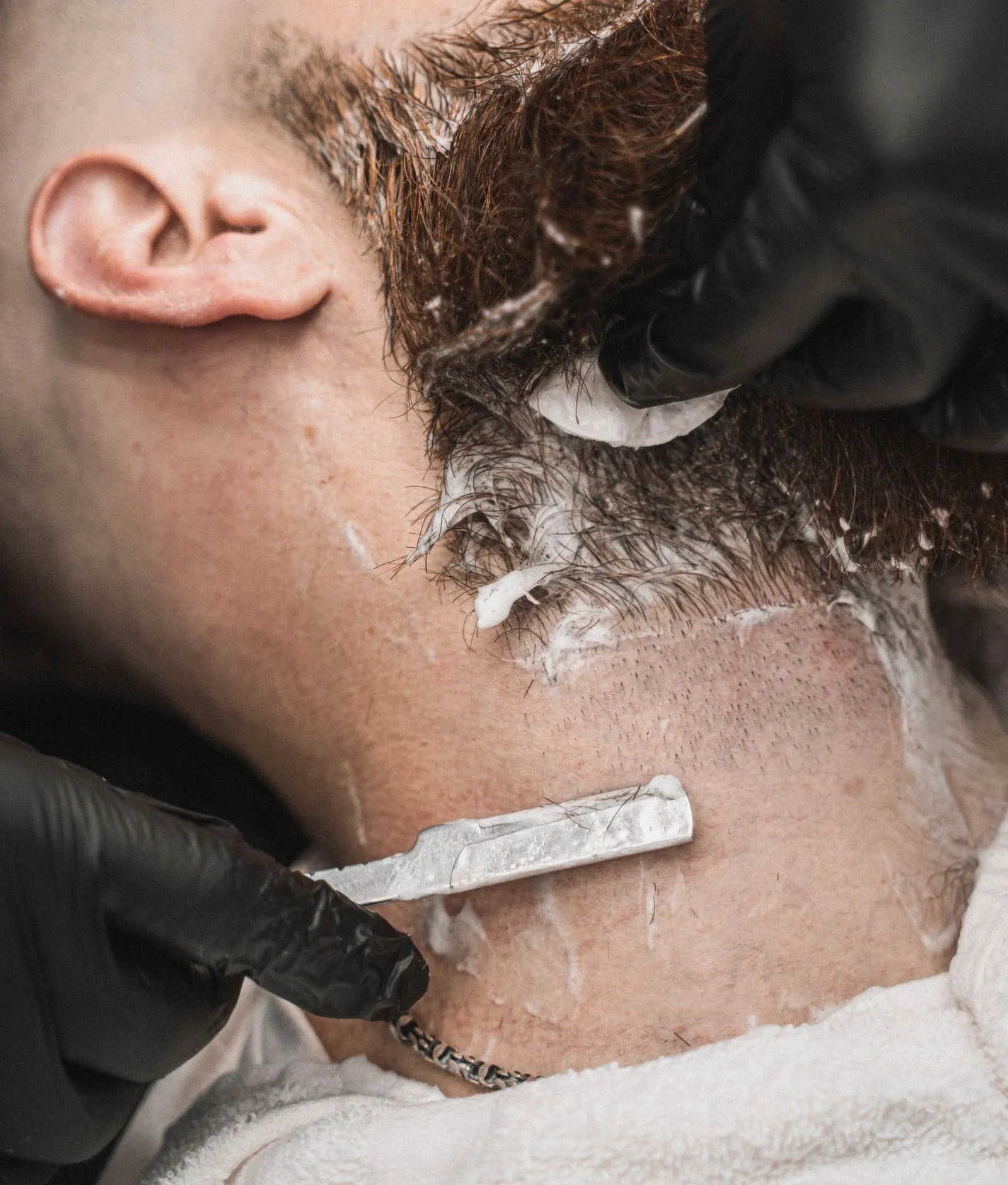 Nassrasur am Hals mit Schaum und Rasiermesser