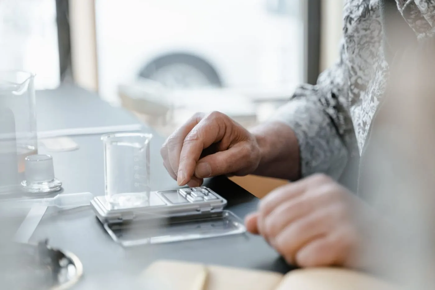 Hände wiegen eine Substanz auf einer Laborwaage ab