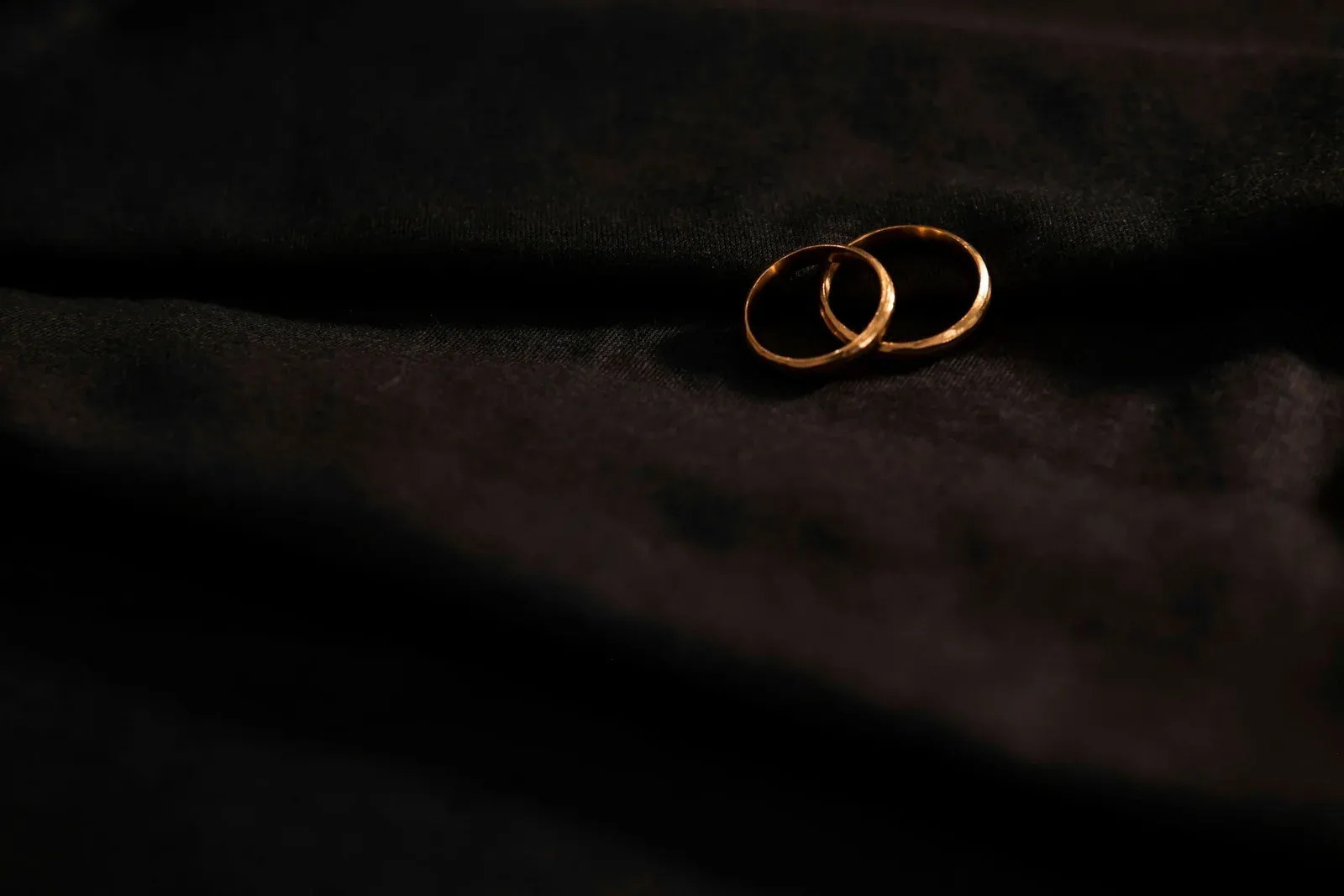 Zwei goldene Trauringe auf dunklem Satin