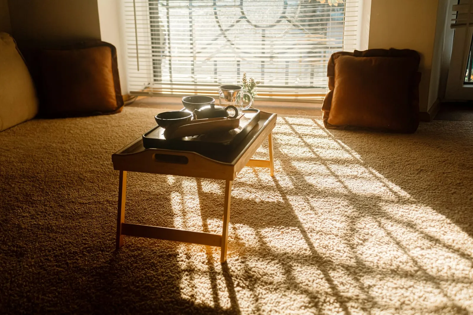 Sonnenlicht fällt durch ein Fenster auf ein Tablett mit Teegeschirr in einem Wohnzimmer