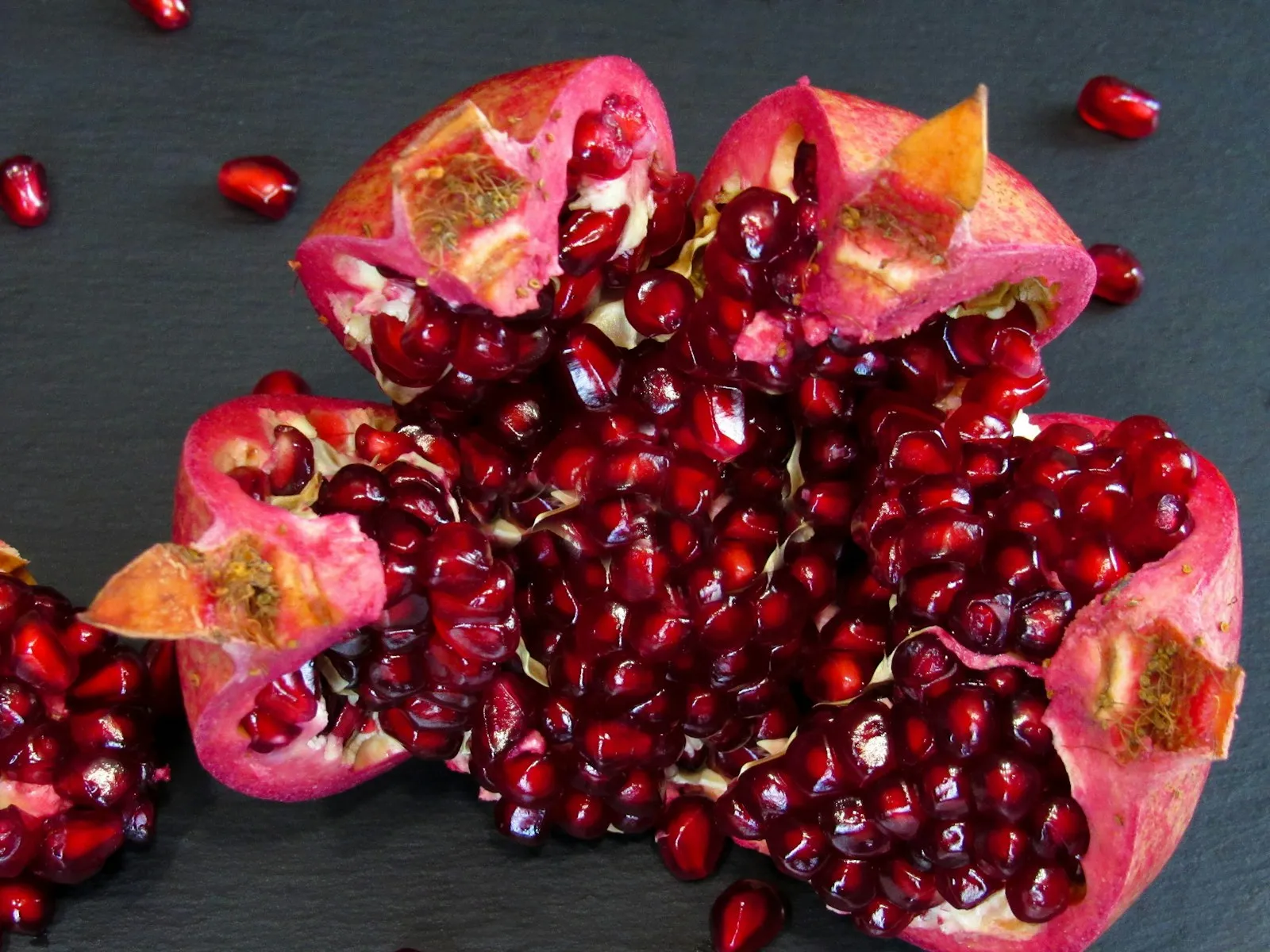 Aufgebrochener Granatapfel auf dunklem Grund