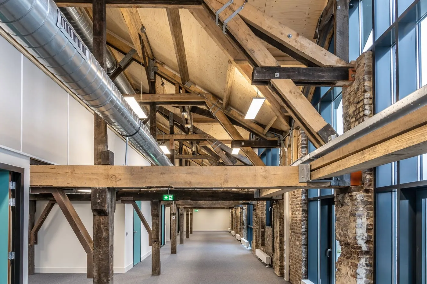 Ausgebautes Dachgeschoss mit alten Holzbalken, hellem Flur und Glaswänden