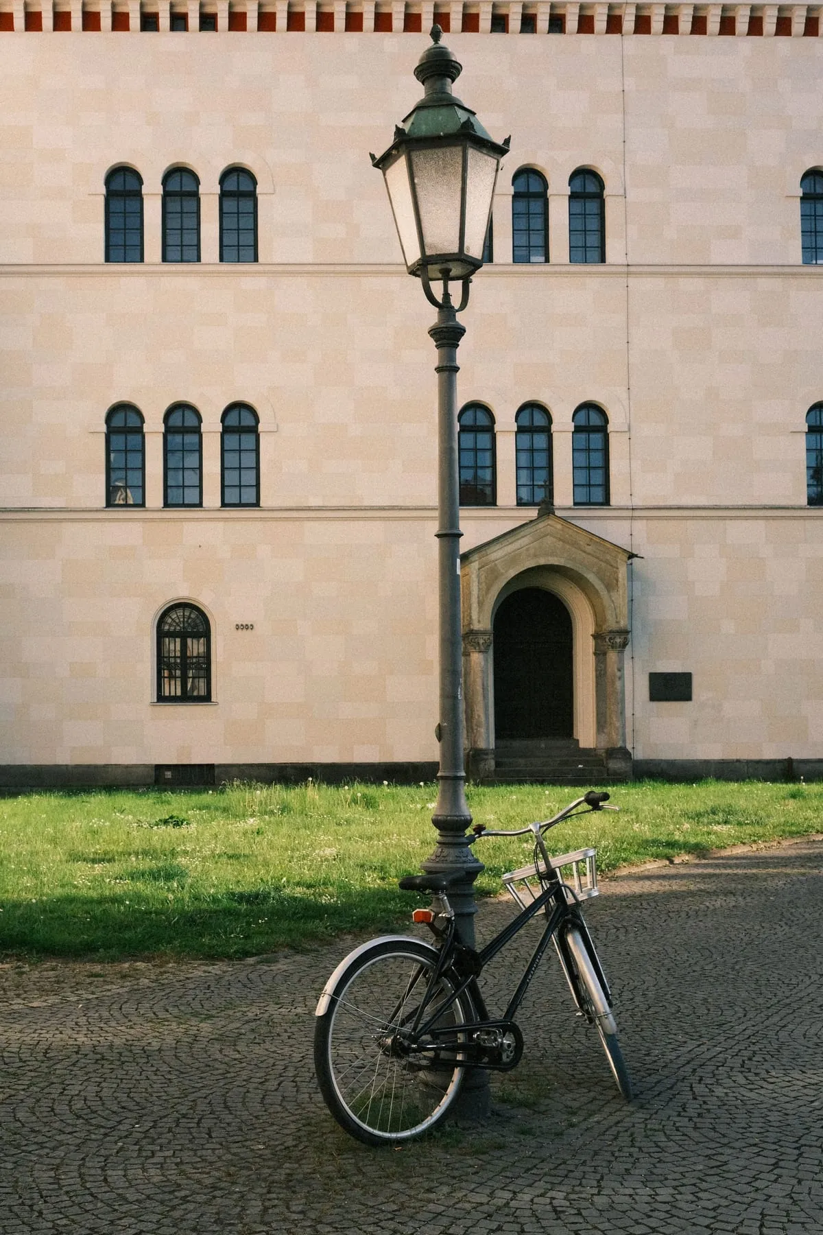 Helle Altbaufassade in München mit Laterne und einem Fahrrad auf dem Pflaster