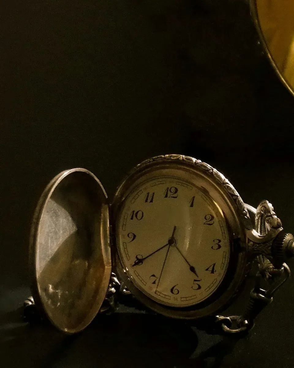 Aufgeklappte Taschenuhr mit weißem Zifferblatt im warmen Licht